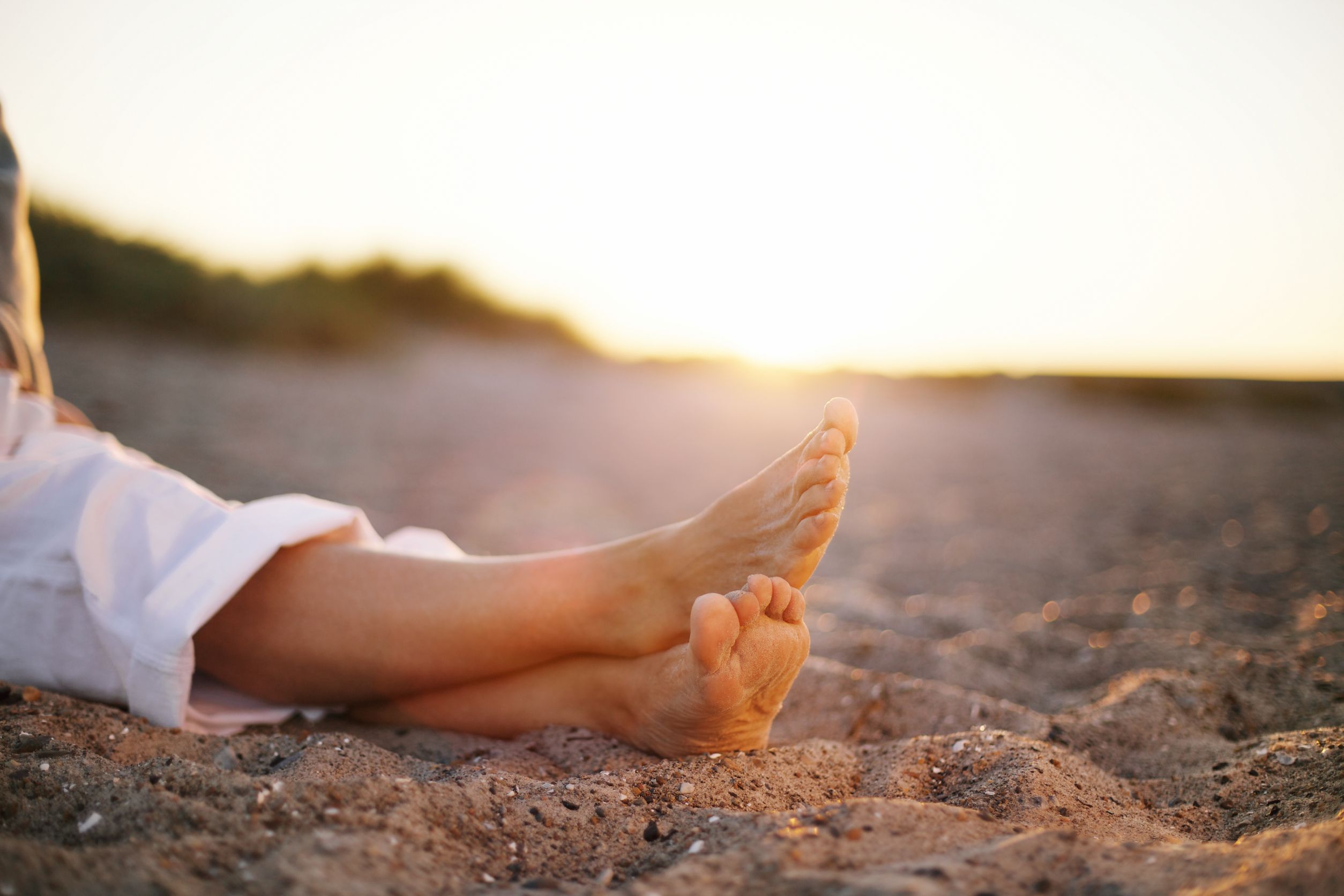 woman's legs crossed on sandy beach