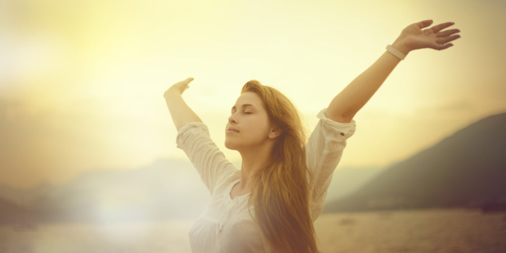 Young woman raising hands in the sun