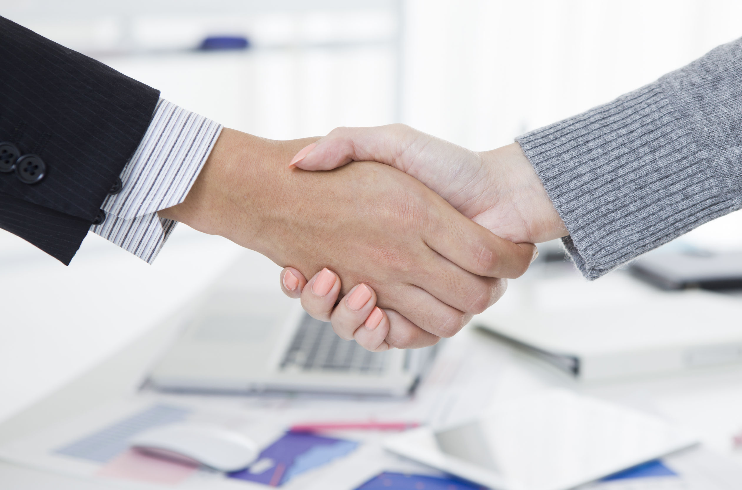 Man and woman formally shaking hands office setting