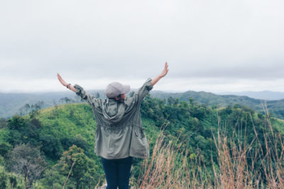 Woman traveler standing on top hill with happiness and refreshed